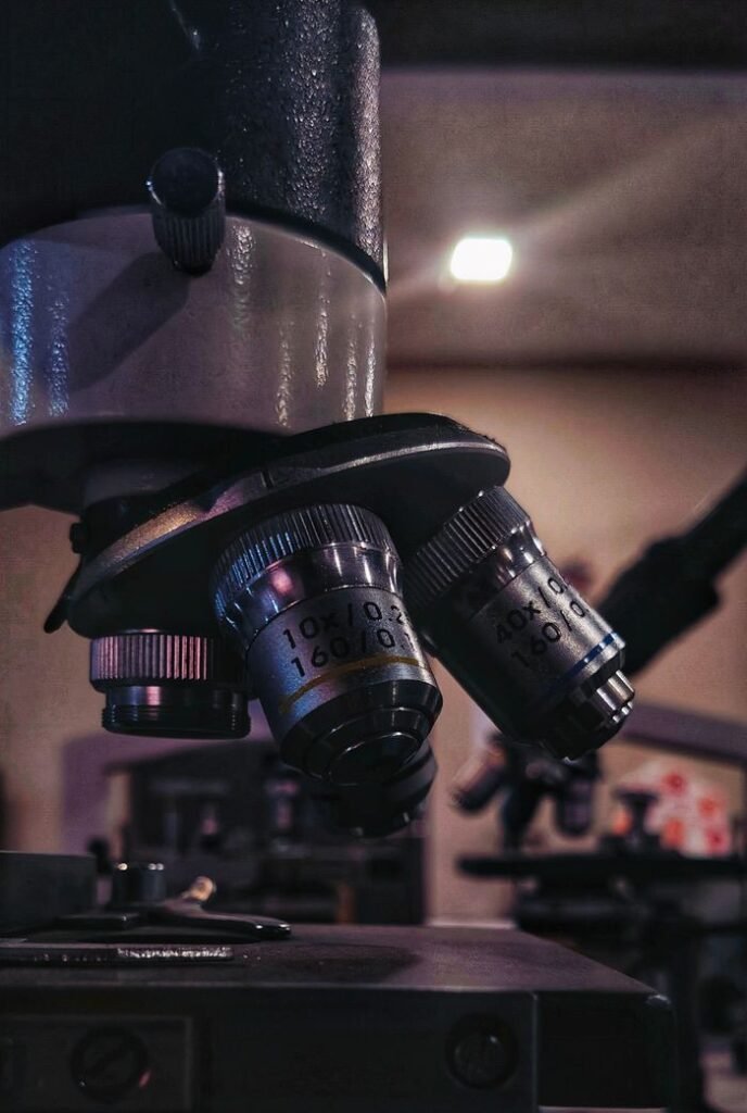Detailed view of microscope lenses in a dimly lit laboratory setting.