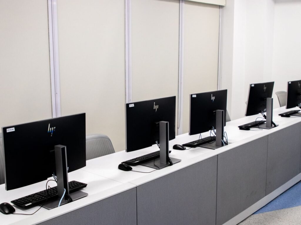 Minimalist open office space featuring empty computer desks with monitors.